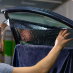 Male car service worker glue window tinting in luxury car detailing car repair the concept of love for cars and a protection